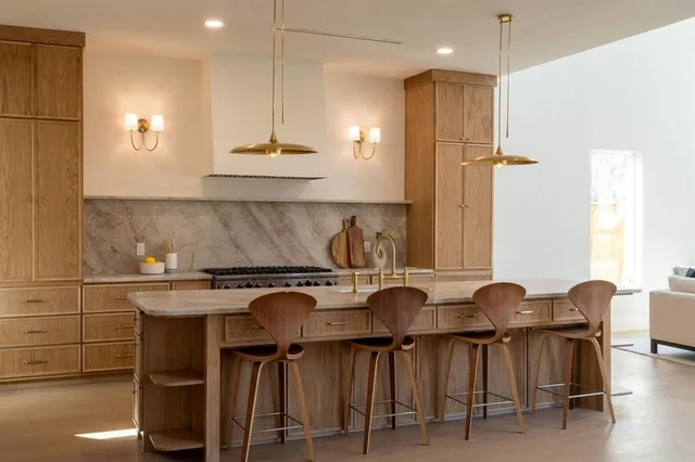 a kitchen with kitchen island granite countertop a table chairs a sink and a refrigerator