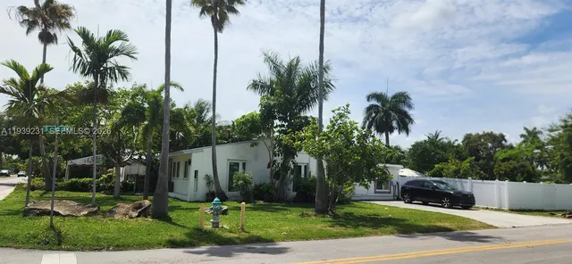 a palm tree sitting in front of a house with a yard
