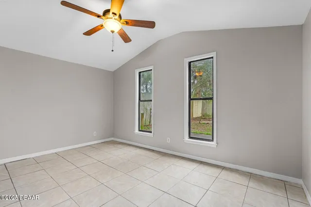 a view of an empty room with window and chandelier fan