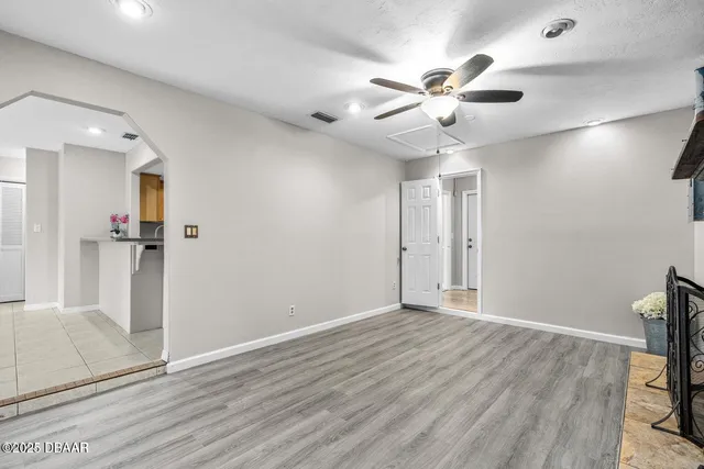 a view of a livingroom with a chandelier fan and wooden floor