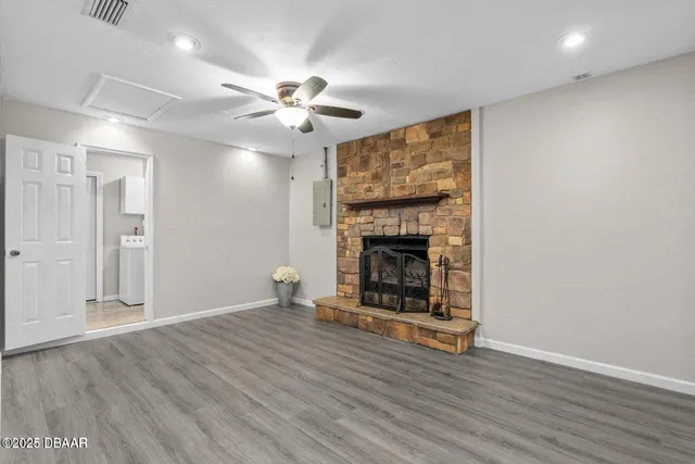 a view of an empty room with wooden floor fireplace and a window