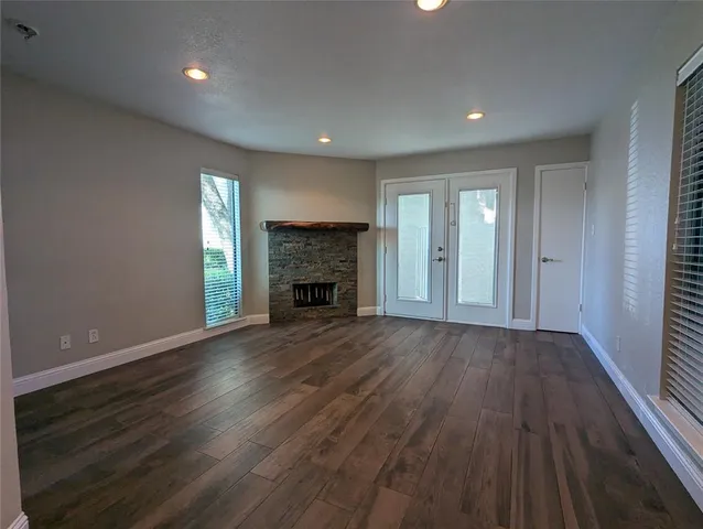 an empty room with wooden floor fireplace and windows