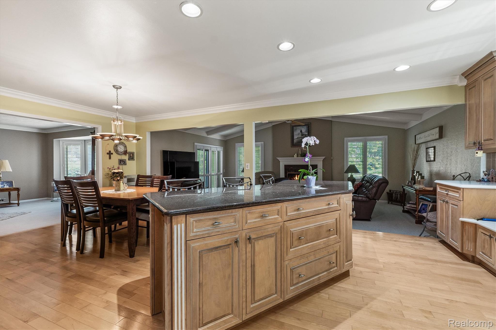 1662 Sumac Drive Rochester, MI 48309 - Photo 12 of 38 Kitchen island with a dark countertop and light wood-finish cabinetry, wood-finish flooring, recessed lighting, and a dining area with a chandelier