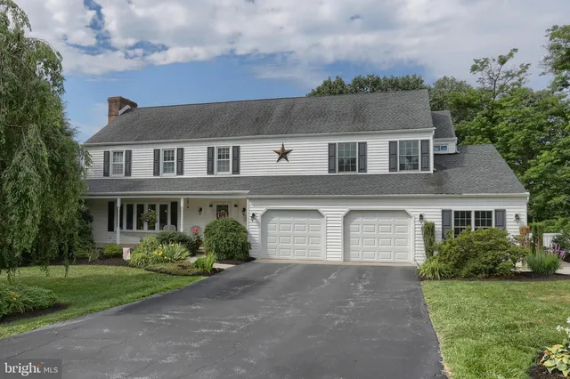 a view of house with a big yard and large trees