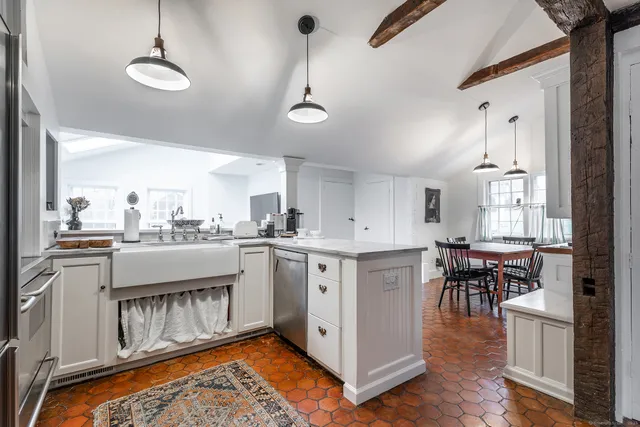 a kitchen with stainless steel appliances granite countertop a stove top oven a sink a dining table and chairs with wooden floor