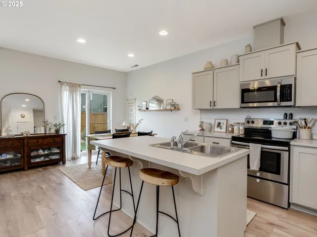 a kitchen with stainless steel appliances kitchen island granite countertop a stove a sink a microwave a refrigerator and cabinets