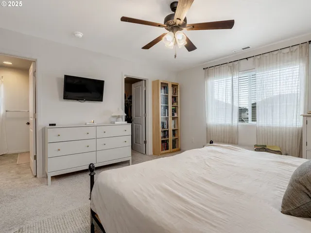 a bedroom with a bed a window and a flat screen tv