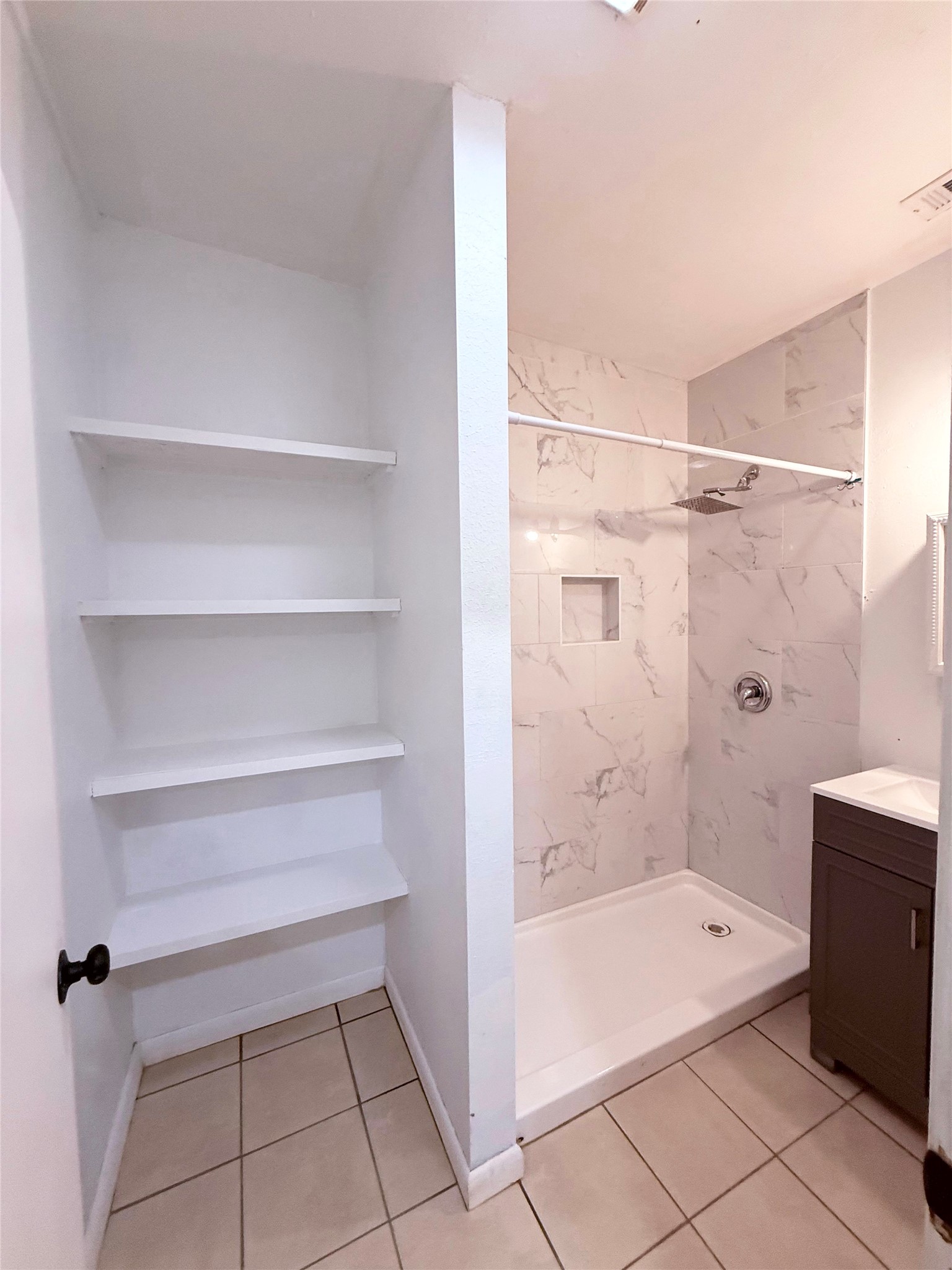 51 Hanging Oak Road Dale, TX 78616 - Photo 14 of 32 Bathroom featuring a tiled shower with a niche, a wall-mounted shower head, and an adjacent vanity with a white countertop