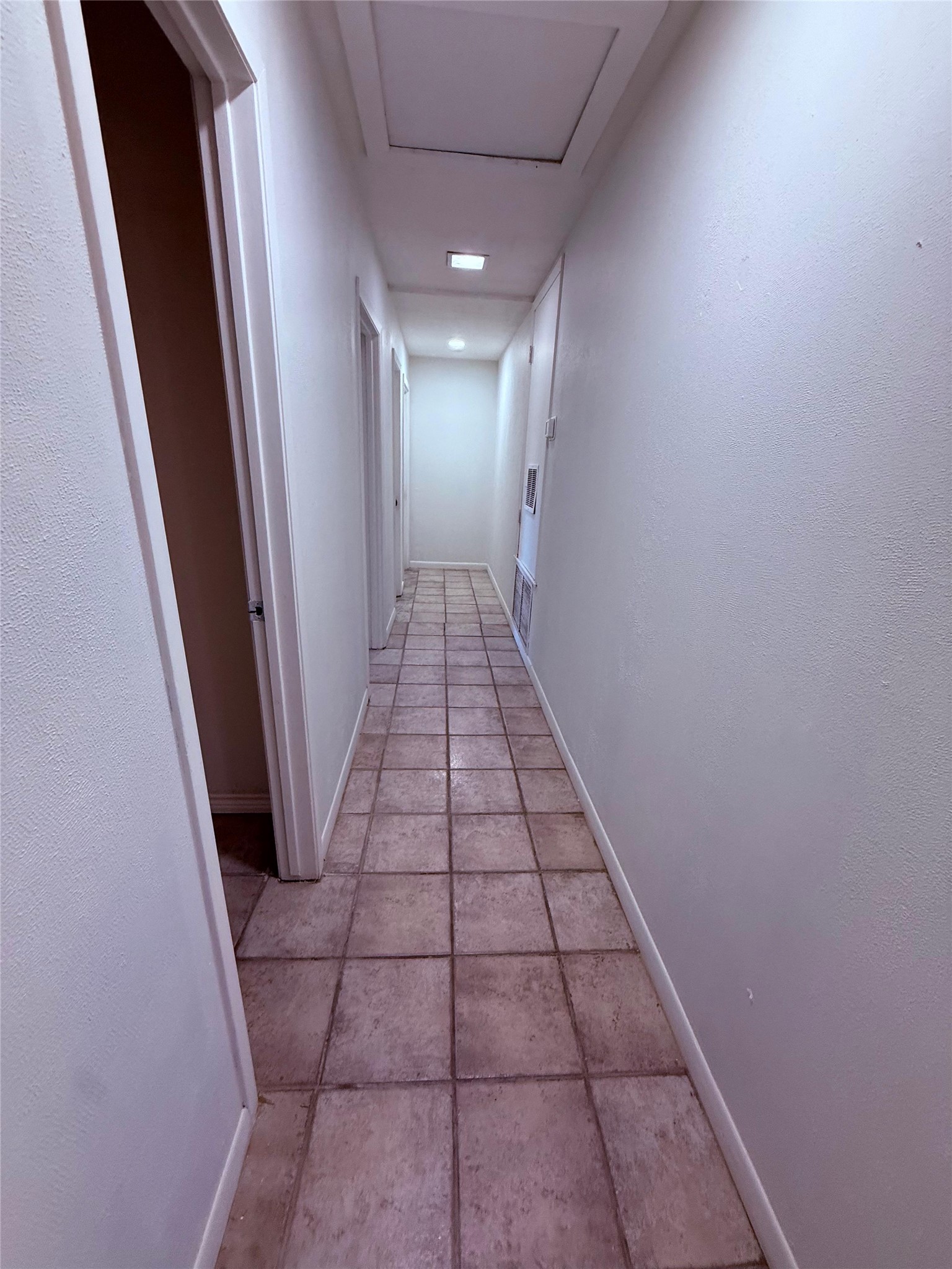 51 Hanging Oak Road Dale, TX 78616 - Photo 15 of 32 Hallway featuring square tile flooring, white baseboards, and multiple doorways