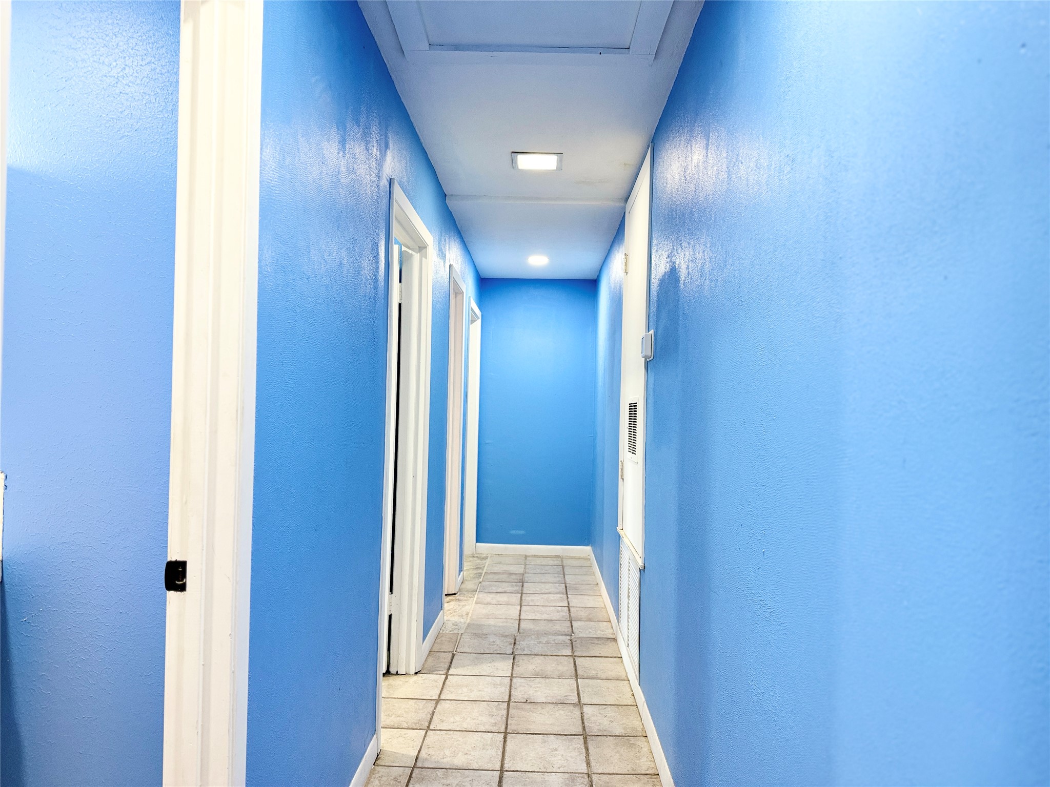 51 Hanging Oak Road Dale, TX 78616 - Photo 20 of 32 Hallway featuring light blue walls, white trim, recessed lighting, and square floor tiles