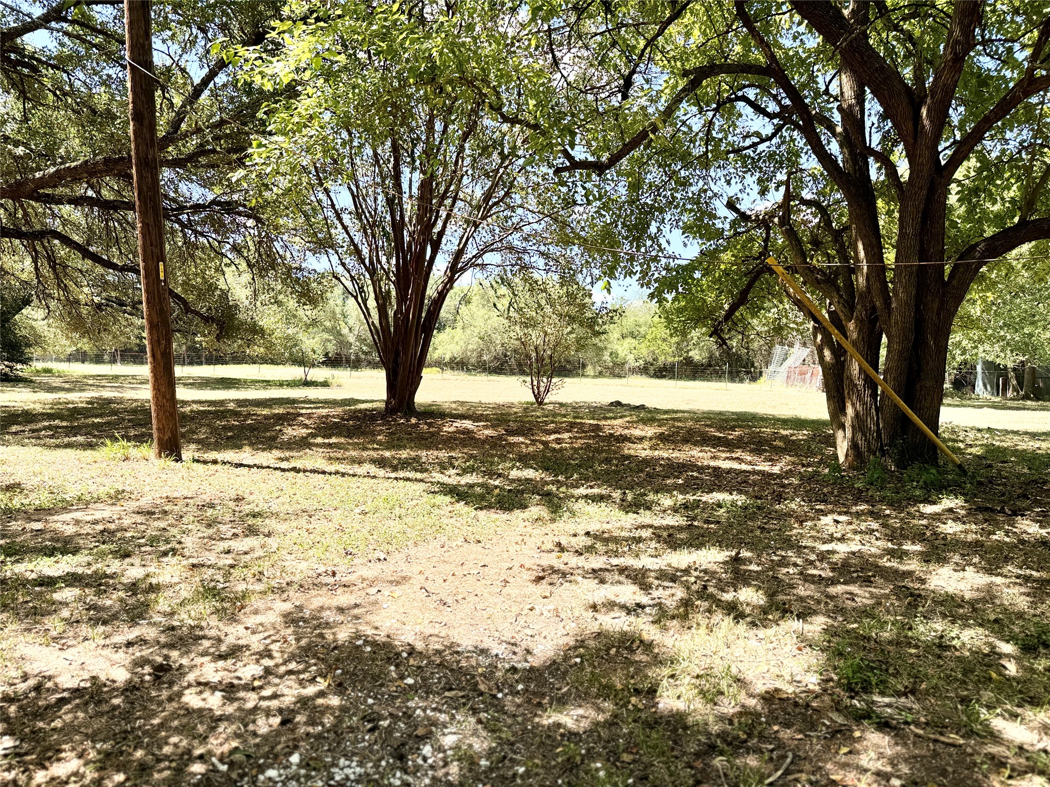 51 Hanging Oak Road Dale, TX 78616 - Photo 30 of 32 Expansive outdoor space featuring mature trees, a utility pole, and a partially visible red structure in the background