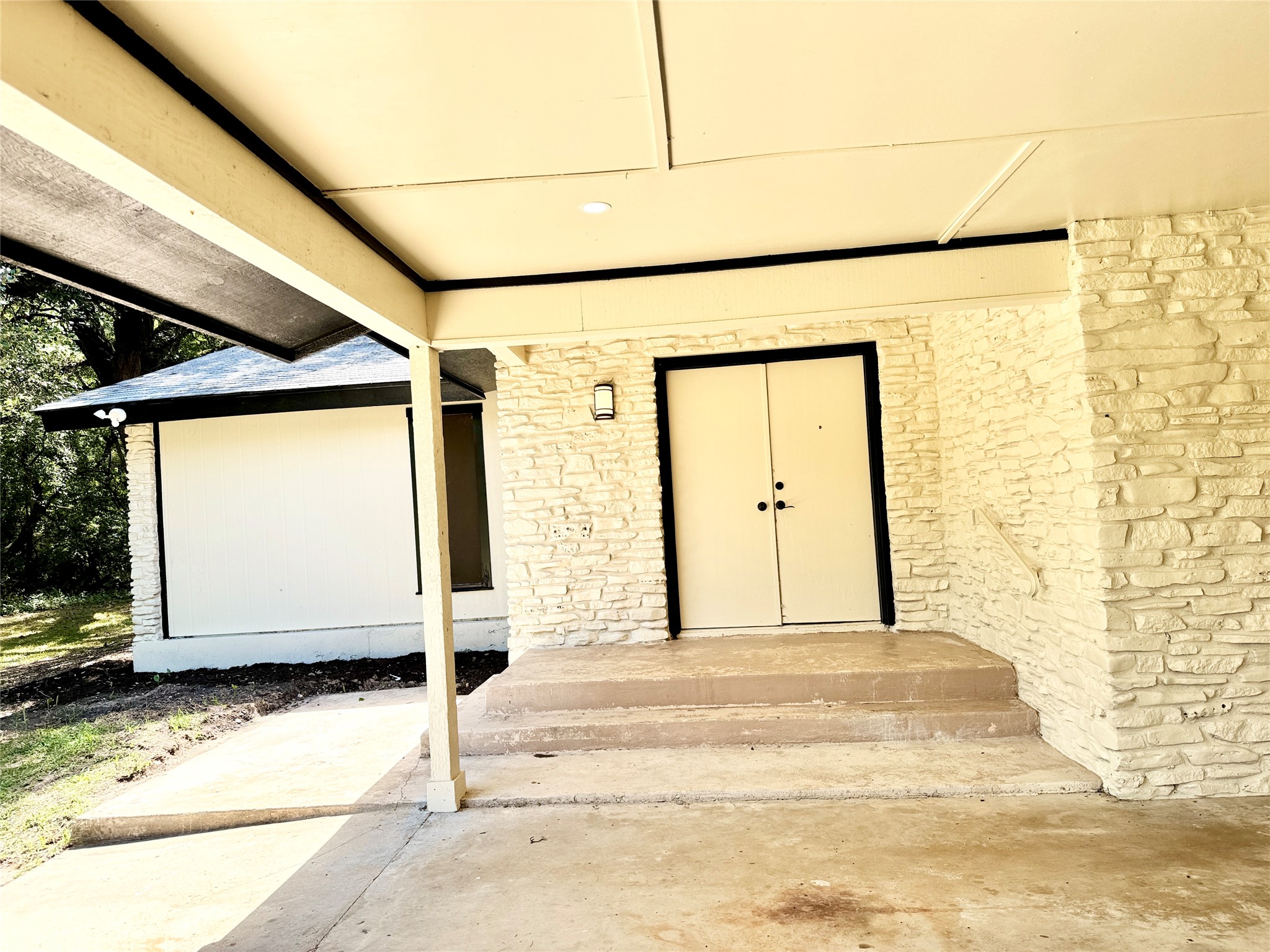 51 Hanging Oak Road Dale, TX 78616 - Photo 31 of 32 Entryway featuring stacked stone siding, double doors with black trim, and a concrete porch with steps and a handrail
