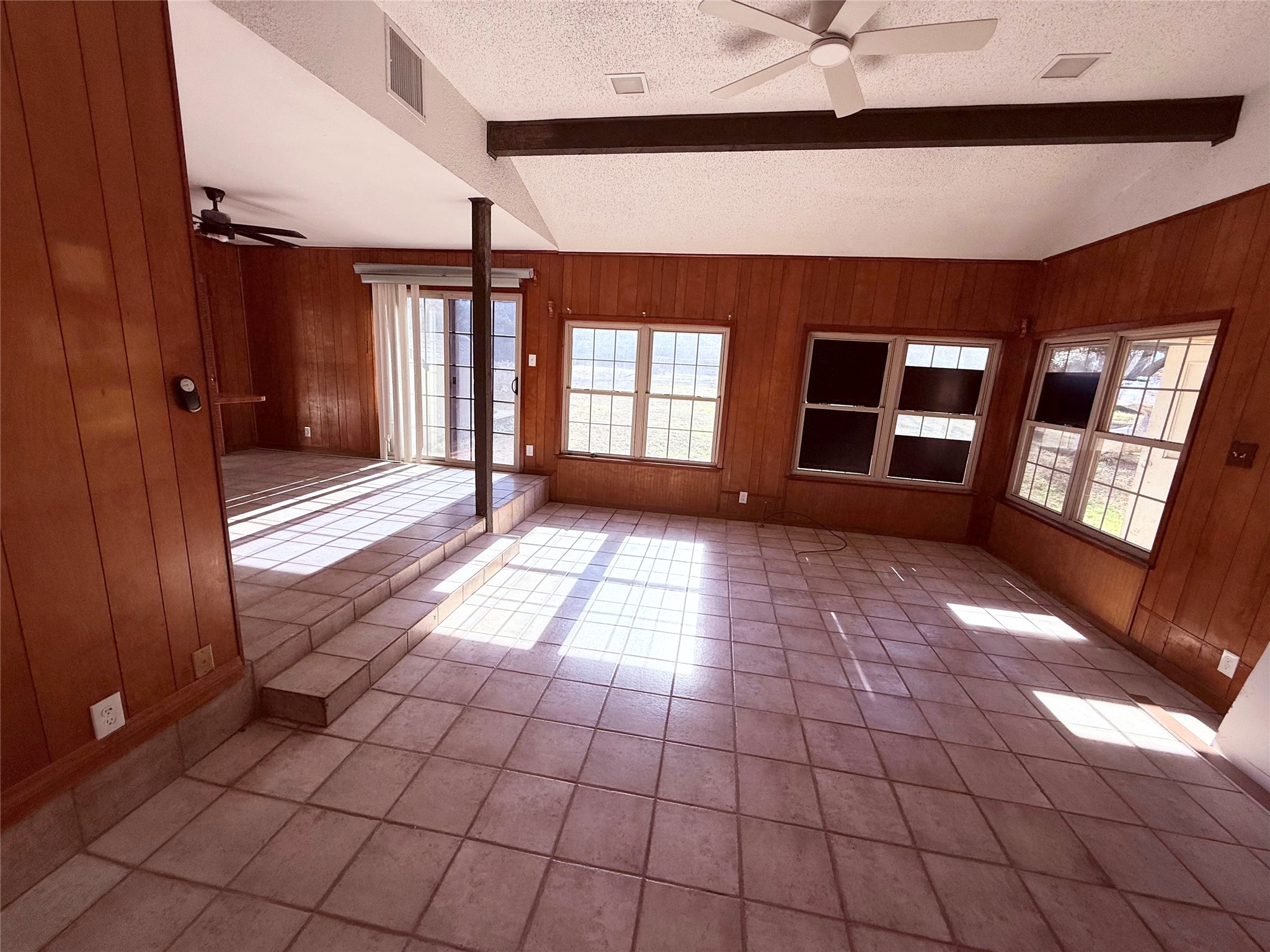 51 Hanging Oak Road Dale, TX 78616 - Photo 6 of 32 Spacious room featuring wood paneling, tile flooring, exposed ceiling beams, a ceiling fan, and multiple windows