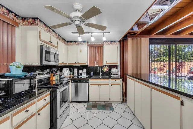 a kitchen with granite countertop a stove a sink and a refrigerator