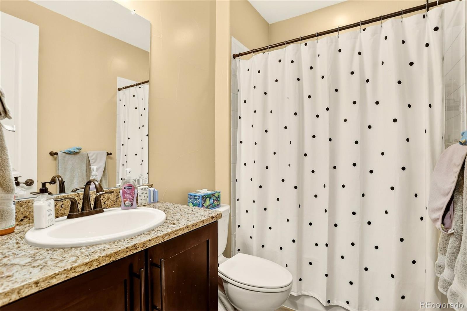 10544 Soulmark Way Highlands Ranch, CO 80126 - Photo 32 of 50 a bathroom with a granite countertop sink a toilet a mirror a vanity and a shower