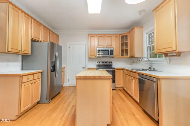 a kitchen with stainless steel appliances granite countertop a refrigerator a sink dishwasher a oven with wooden cabinets and floor