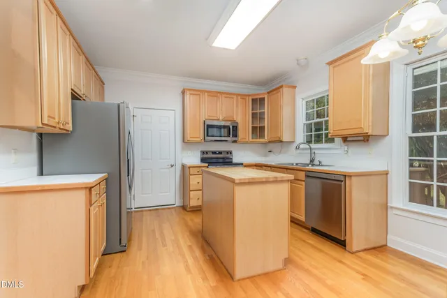 a kitchen with stainless steel appliances granite countertop a refrigerator a stove top oven a sink and dishwasher with wooden floor