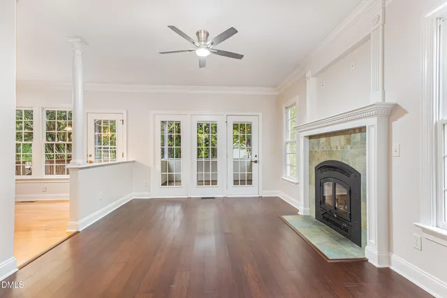 a view of an empty room with wooden floor fireplace and a window