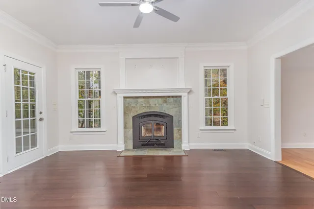 an empty room with wooden floor fireplace and windows