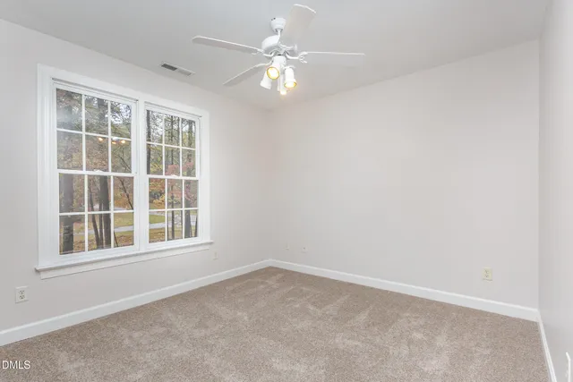 an empty room with a chandelier fan and windows