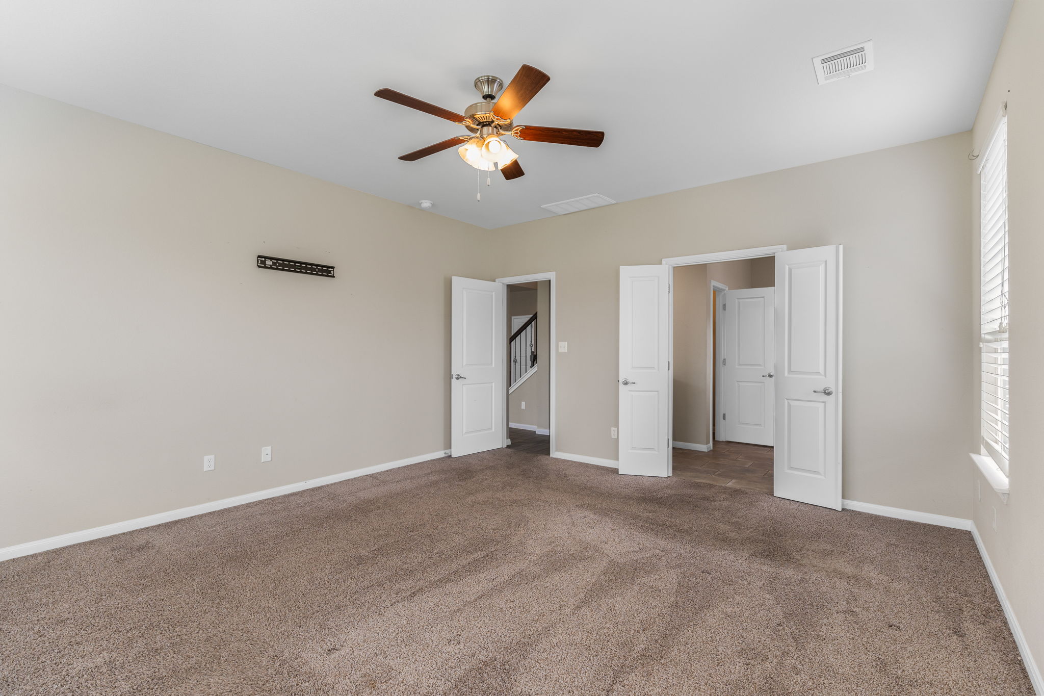 301 Rimrock Court Bastrop, TX 78602 - Photo 12 of 21 Warm, neutral carpeting and a ceiling fan define this inviting primary bedroom.