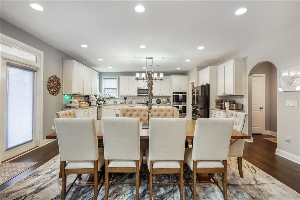 4450 Woodward Walk Lane Suwanee, GA 30024 - Photo 18 of 52 a dining room with stainless steel appliances kitchen island granite countertop a dining table chairs and a refrigerator