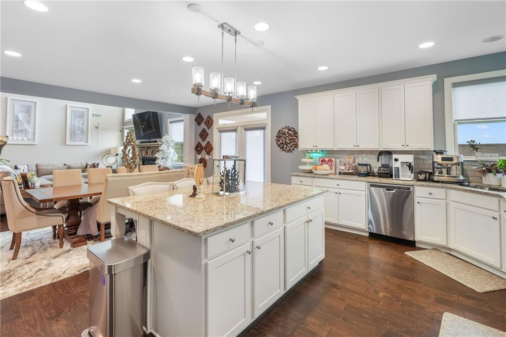 4450 Woodward Walk Lane Suwanee, GA 30024 - Photo 20 of 52 a kitchen with stainless steel appliances granite countertop a sink dishwasher a stove and white cabinets with wooden floor