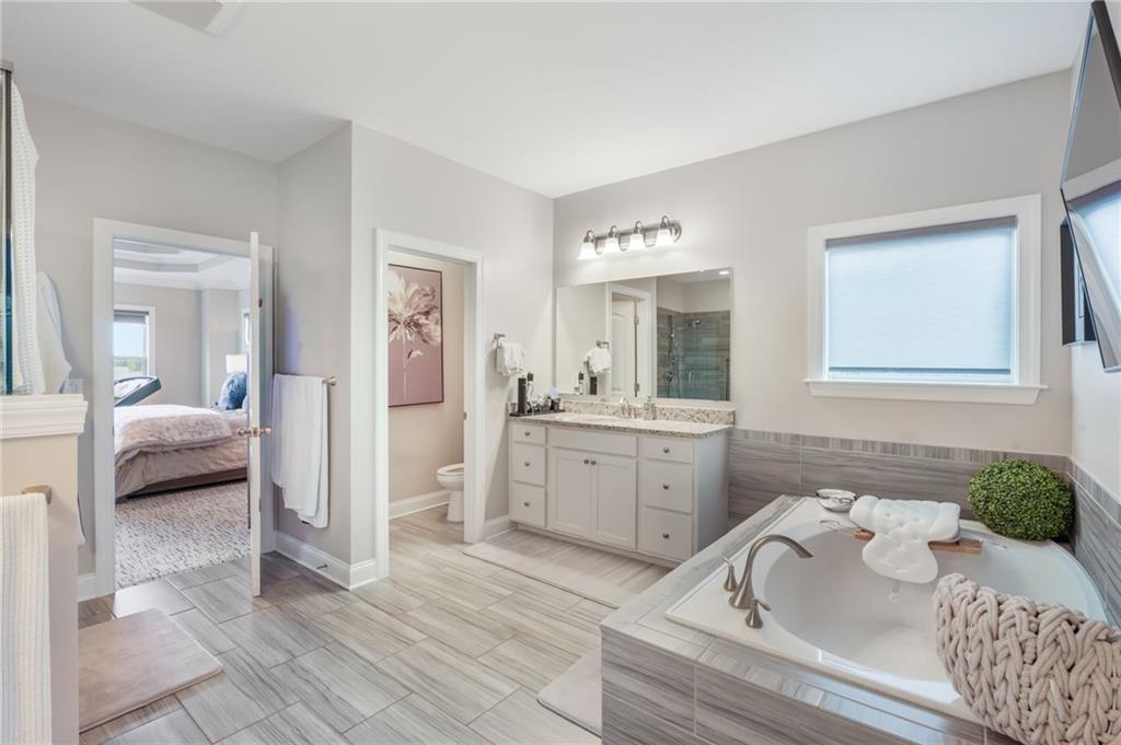 4450 Woodward Walk Lane Suwanee, GA 30024 - Photo 32 of 52 a en suite spacious bathroom with a tub double vanity and view bedroom