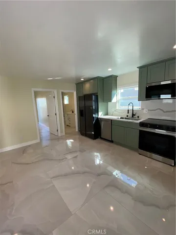 a large kitchen with a stove a sink dishwasher and a refrigerator with wooden floor