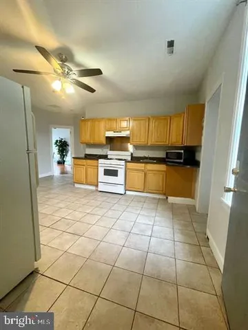 a large kitchen with granite countertop a large counter top space appliances and cabinets