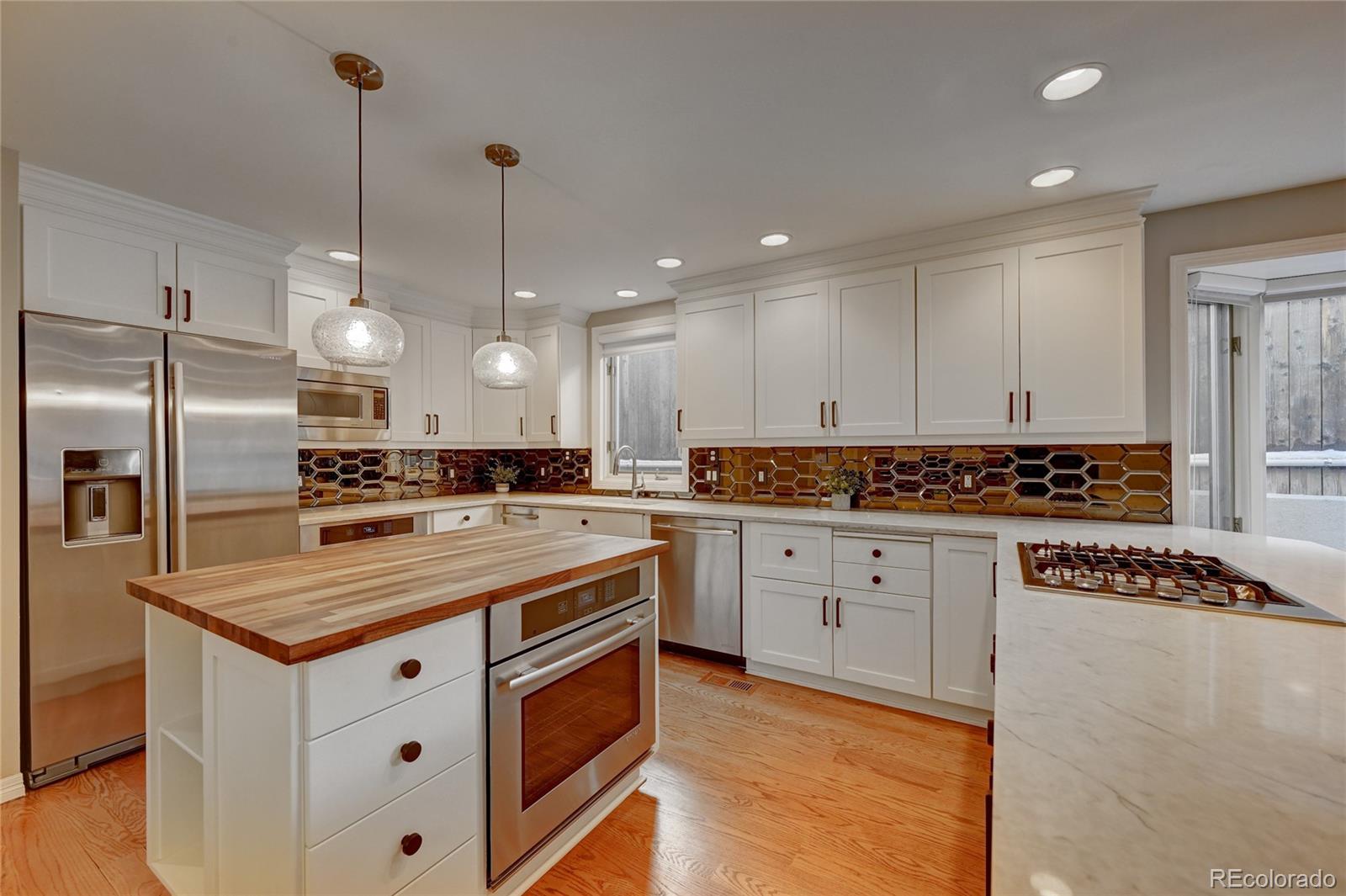 358 Steele Street Denver, CO 80206 - Photo 10 of 30 a kitchen with stainless steel appliances granite countertop a sink a stove and a refrigerator