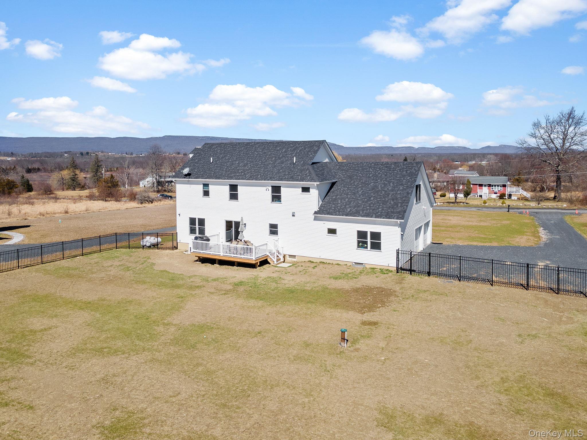 10 Harrier Ridge Drive Wallkill, NY 12589 - Photo 42 of 46 Back of house featuring a deck with mountain view, a fenced backyard, roof with shingles, driveway, and a garage