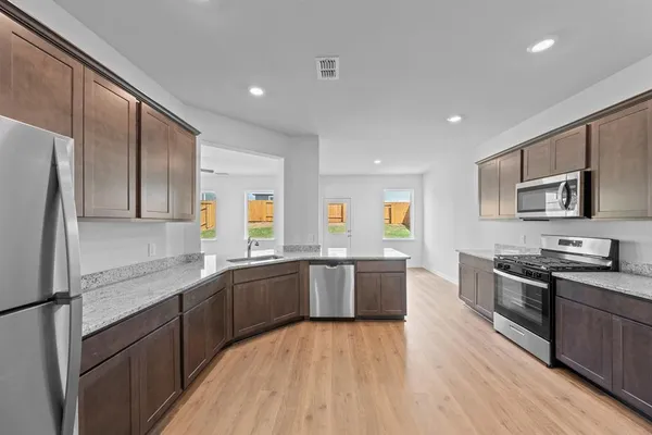 a kitchen with stainless steel appliances granite countertop hardwood floor sink stove dining table and chairs