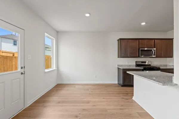 a kitchen with granite countertop a stove top oven a sink dishwasher and a refrigerator with wooden floor