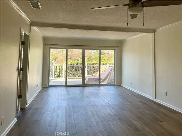 a view of an empty room with a window and wooden floor