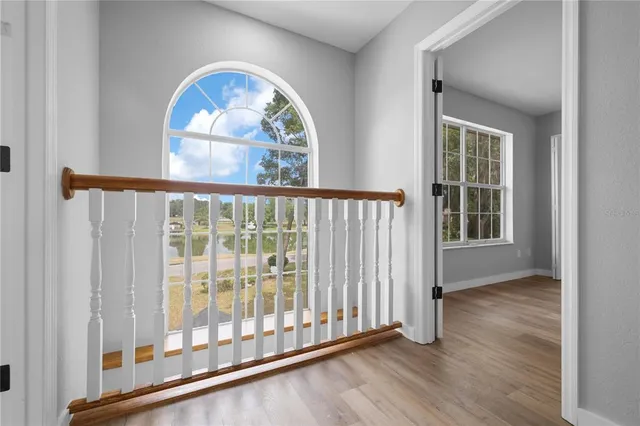 an empty room with wooden floor fan and windows