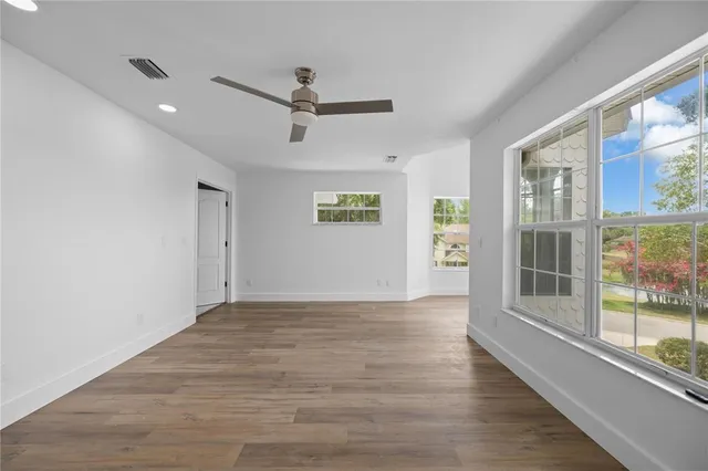 a view of an empty room with a window and wooden floor