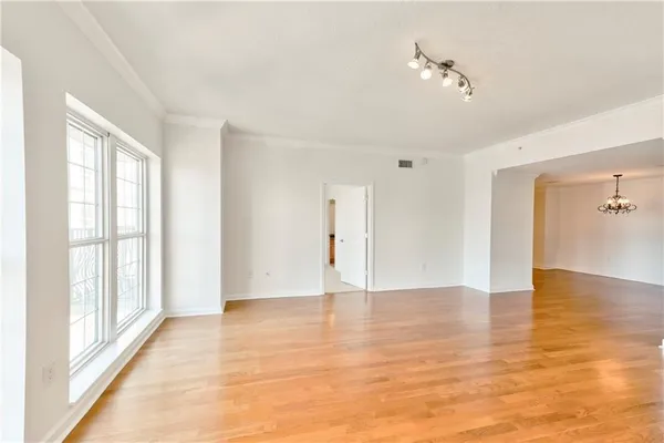 a view of an empty room with window and wooden floor