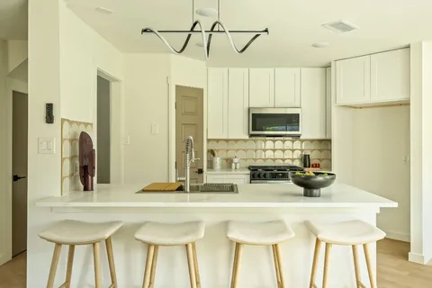 a kitchen with stainless steel appliances a sink a refrigerator and a white cabinets
