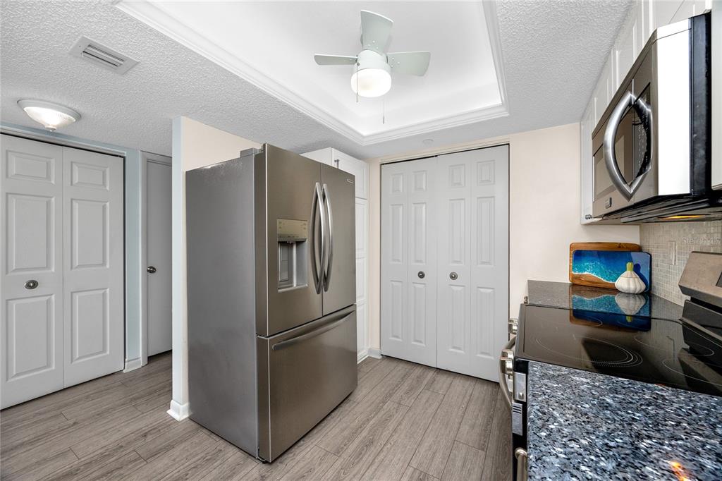 1300 Gulf Boulevard, Unit 301 Indian Rocks Beach, FL 33785 - Photo 7 of 46 a kitchen with stainless steel appliances granite countertop a refrigerator a stove and a sink with wooden floor