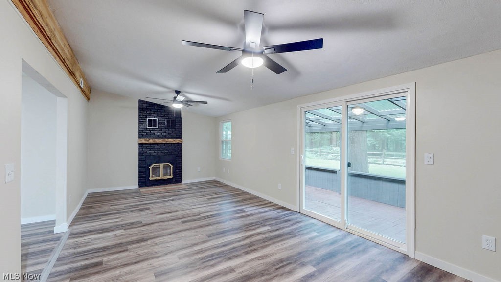 18620 Shaw Road Chagrin Falls, OH 44023 - Photo 22 of 44 Spacious living area featuring wood-finish flooring, a black brick fireplace with a wood mantle, and exposed beam accent