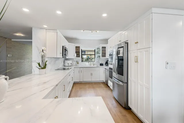 a large white kitchen with a large window and stainless steel appliances