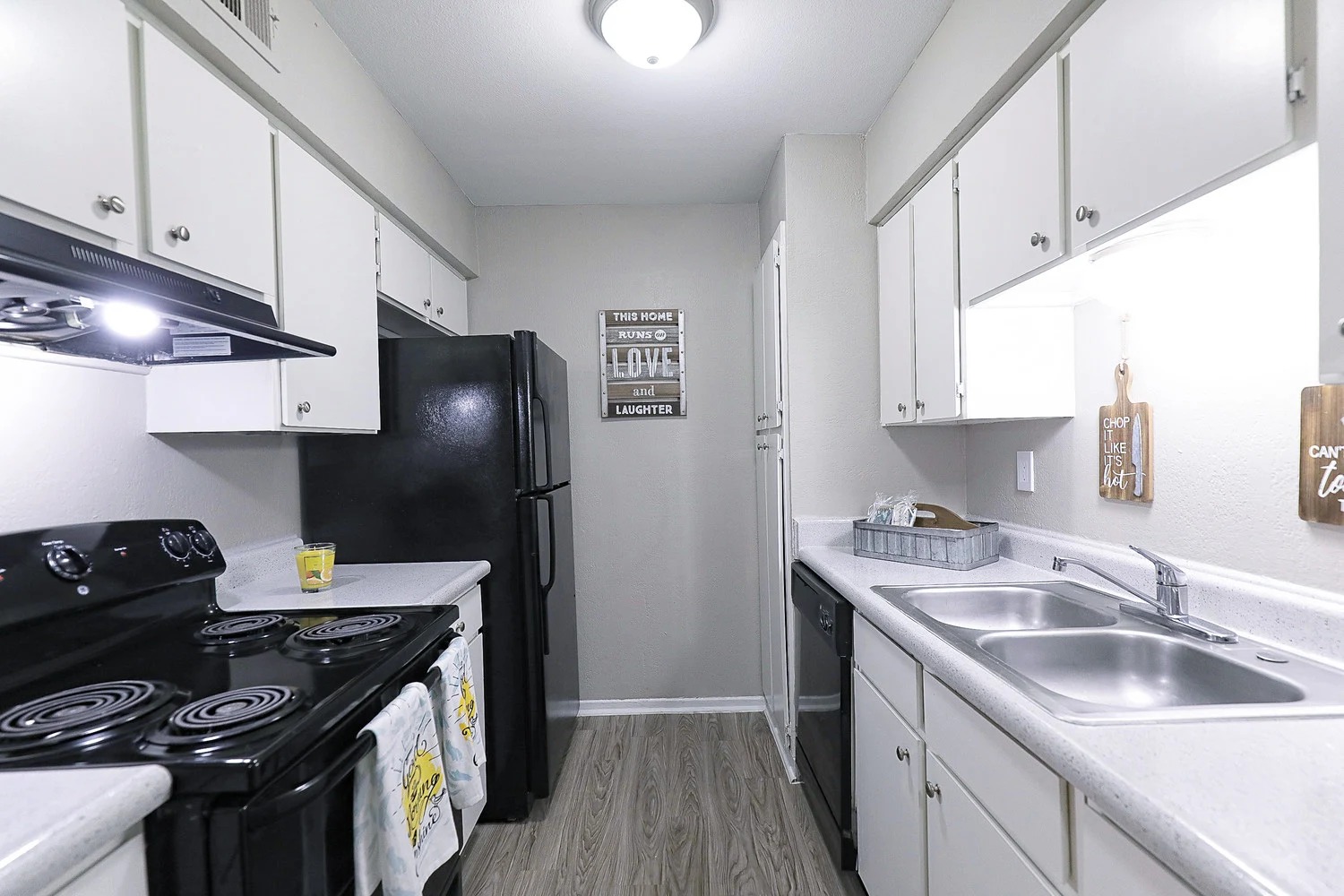 8100 North Mopac Expressway, Unit 5223 Austin, TX 78759 - Photo 15 of 28 Kitchen featuring black appliances, light countertops, white cabinets, under cabinet range hood, and light wood finished floors