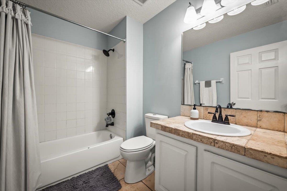 1701 Keswick Road St. Augustine, FL 32084 - Photo 21 of 57 a bathroom with a granite countertop sink a toilet a mirror a bathtub and shower