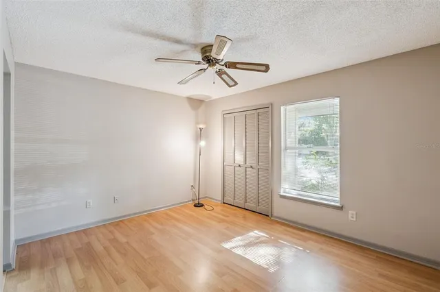 a view of empty room with wooden floor and ceiling fan