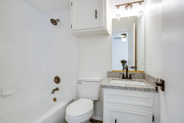 a bathroom with a granite countertop toilet sink and mirror
