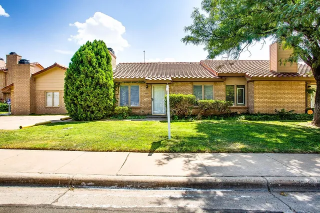 a view of a house with a yard and a large tree center