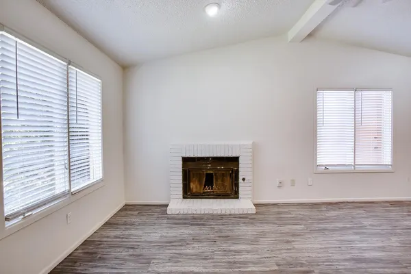 an empty room with windows and fireplace