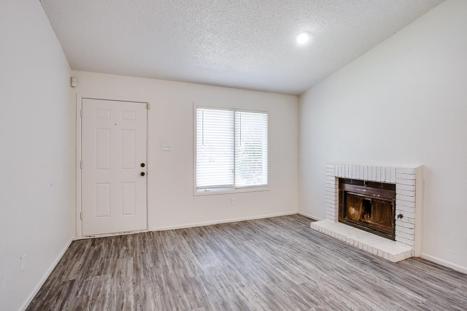 4749 2nd Street Lubbock, TX 79416 - Photo 4 of 13 an empty room with wooden floor a fireplace and windows
