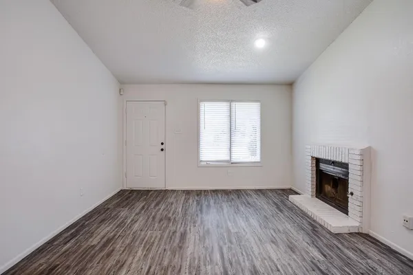 an empty room with wooden floor a fireplace and windows